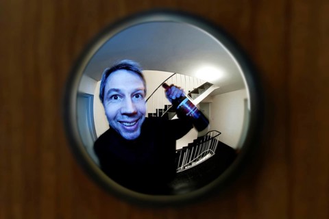 View through door viewer into a staircase of a big tenement, peephole, spyhole, with a man in front