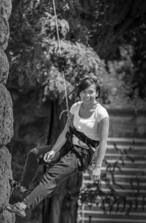 A woman climbing a rock face, secured with a rope and harness, Hohenzollern Bridge, Cologne Deutz,