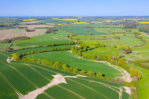 Aerial view over rural bocage landscape with fields and pastures, patchwork of plots surrounded by