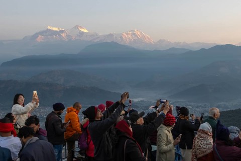 Asian-looking tourists watching and photographing sunrise as well as shooting selfies on the second