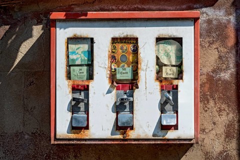 Old rusty triple chewing gum machine on a wall, vending machine for children for chewing gum and