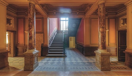 Magnificent entrance area with marble columns and a grand staircase in warm light, Villa Woodstock,