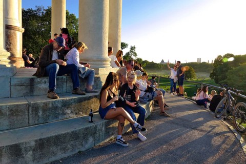 People enjoying the autumn sun at the Monopteros in the English Garden, with a view of the Munich