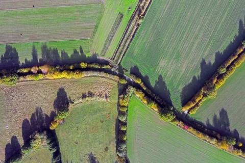 Aerial view over rural roads and bocage landscape with fields, meadows and pastures, patchwork of