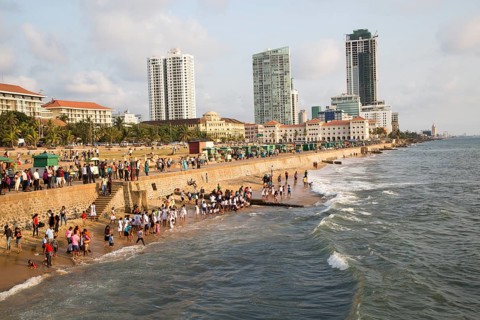 School children paddle in the sea on small sandy beach at Galle Face Green, Colombo, Sri Lanka,