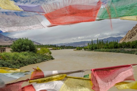 Mid-summer view of the Indus River, seen from the Buddhist prayer flags decorated bridge in Central
