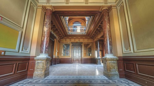 Symmetrical hallway with decorative ceiling and marble floor, flanked by columns, Villa Woodstock,