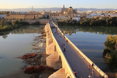 Roman bridge spanning river Rio Guadalquivir with Mezquita cathedral buildings, Cordoba, Spain,