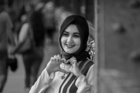 Friendly smiling woman in hijab making a heart sign with her hands, Hohenzollernbruecke, Cologne