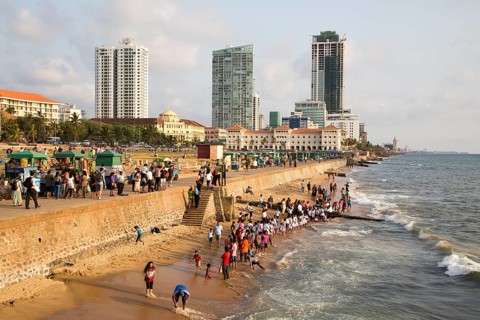 School children paddle in the sea on small sandy beach at Galle Face Green, Colombo, Sri Lanka,