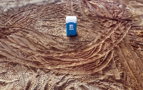 Traces of truck tyres and construction machinery circle a toilet in the middle of a construction