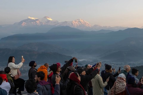 Asian-looking tourists watching and photographing sunrise as well as shooting selfies on the second