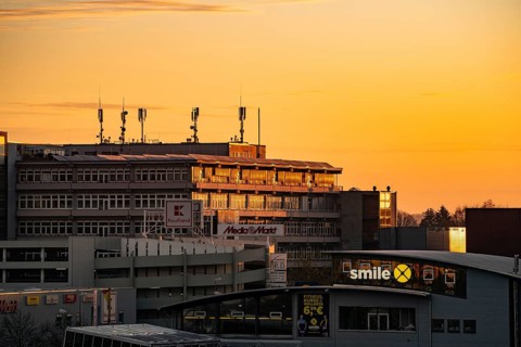 Building with antennas on the roof against a sky flooded with warm light at sunset, Wilferdinger