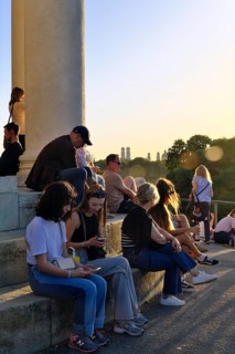 People enjoying the autumn sun at the Monopteros in the English Garden, with a view of the Munich