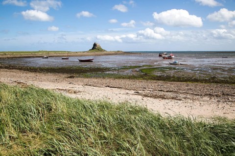 Castle and boats at low tide, Holy Island, Lindisfarne, Northumberland, England, UK