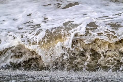 Wave crashing /rolling on beach during winter storm along North Sea coast in Zeeland, Netherlands