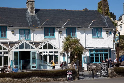 People sitting outside The Rising Sun pub, St Mawes, Cornwall, England, UK