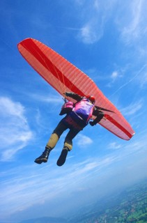 Paragliding pilot in a curve high above ground, camera on fishing lines fixed at the glider,