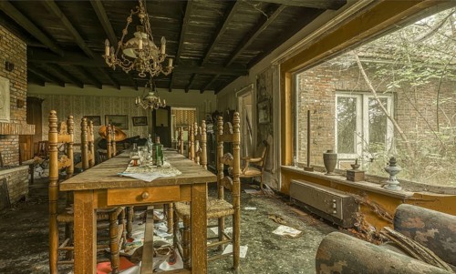 A damaged dining room with destroyed furniture and windows letting in daylight, Maison Limmi, Lost
