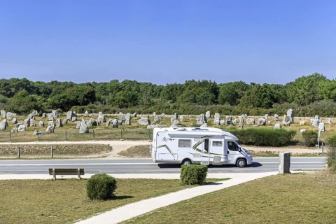 Motorhome, camper van driving past the Menec alignments, megalithic site among the Carnac standing