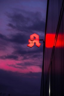 Illuminated pharmacy sign in front of a stormy sky on a facade in Duesseldorf, Germany, Europe