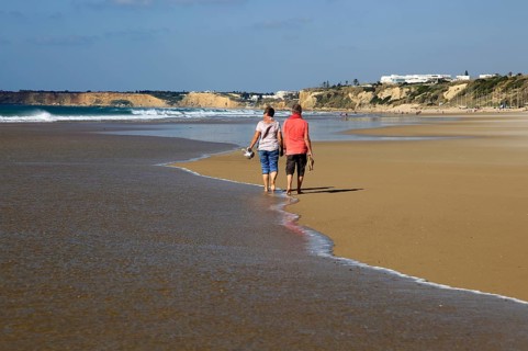 Man and woman walking together on sandy beach at Conil de la Frontera, Cadiz Province, Spain,