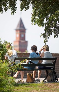 Swedish woman sitting on a park bench, behind them the tower of the town hall, Helsingborg, Skane