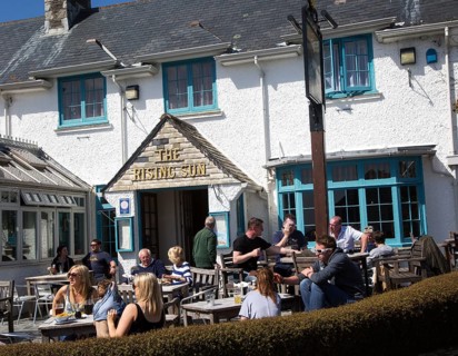 People sitting outside The Rising Sun pub, St Mawes, Cornwall, England, UK
