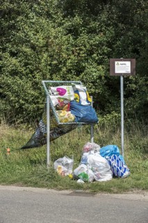 Illegal dumping of household refuse bags in net along roadside meant for throwing in cans and