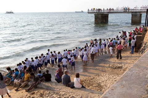 School children paddle in the sea on small sandy beach at Galle Face Green, Colombo, Sri Lanka,