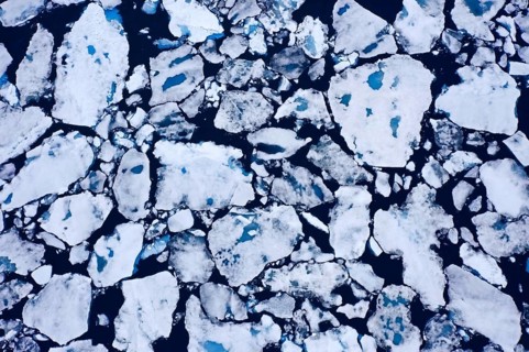 Aerial view over sea ice, drift ice, ice floes with melt ponds containing freshwater in the Arctic
