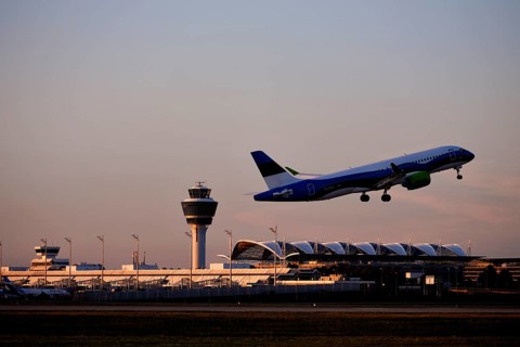 AirBaltic Airbus A220 taking off on Runway South with Terminal 1 and Tower in the sunset, Munich