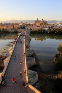 Roman bridge spanning river Rio Guadalquivir with Mezquita cathedral buildings, Cordoba, Spain,
