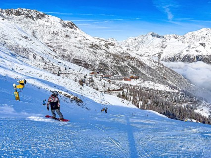 Snowboarders on the ski slope in front of the Hochsoelden hotel settlement in the Soelden ski