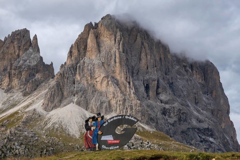 Traditional traditional costume couple advertising sign on the Sella Pass, behind Sassolungo, South