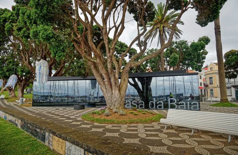 Modern glass building opposite historic houses in a green park, Horta, Faial Island, Azores,