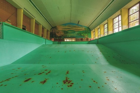 A dilapidated, empty swimming pool with rust stains on the floor, deserted atmosphere, Bad am Park,