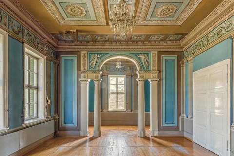 Sunlight floods a room with columns and an ornate ceiling with chandelier, Schachtrupp Villa, Lost