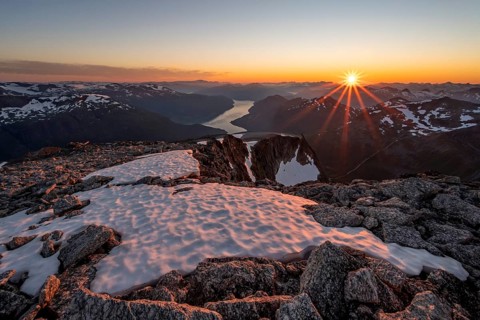 View of mountains and fjord Faleidfjorden, sun star at sunset, summit of Skala, Loen, Norway,