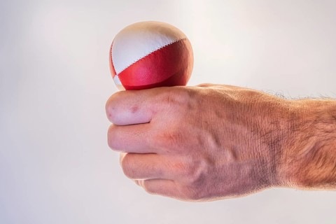 Hand with a juggling ball in front of a white background, studio shot, Germany, Europe