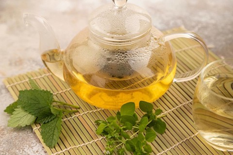 Green oolong tea with herbs in glass on brown concrete background. Healthy drink concept. Side