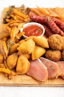Set of snacks: sausages, fried potatoes, meat balls, dumplings, basturma on a cutting board on a