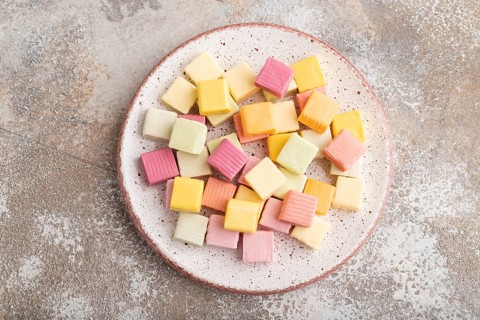 Various fruit jelly chewing candies on plate on brown concrete background. apple, banana,