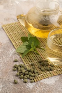 Green oolong tea with herbs in glass on brown concrete background. Healthy drink concept. Side
