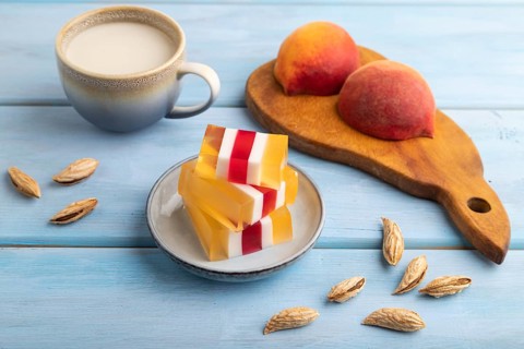 Almond milk and peach jelly on blue wooden background. side view, close up