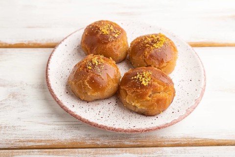 Homemade traditional turkish dessert sekerpare with almonds and honey on white wooden background.