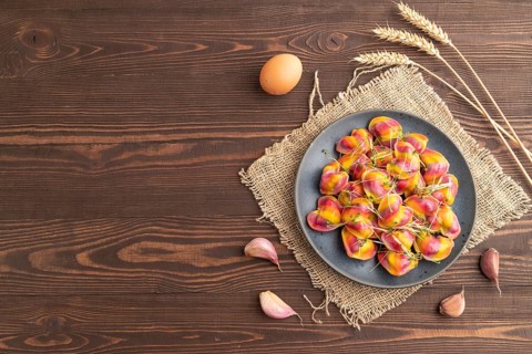 Rainbow colored dumplings with pepper, herbs, microgreen on brown wooden background and linen