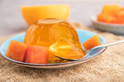 Papaya and orange jelly on gray concrete background and linen textile. side view, close up,