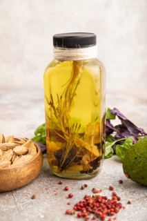 Sunflower oil in a glass jar with various herbs and spices, sesame, rosemary, avocado, basil,