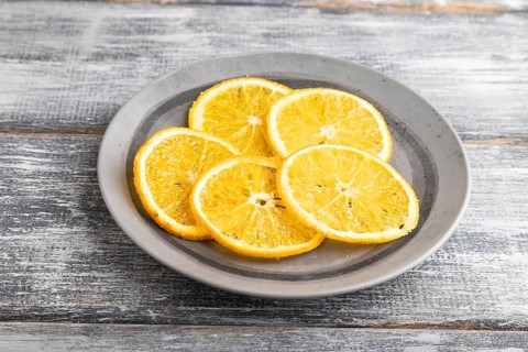 Orange chips on a gray plate on a gray wooden background. Side view, close up